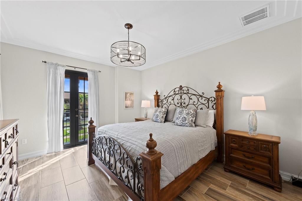 9076 Rialto Street, Unit 6204 Naples, FL 34113 - Photo 15 of 50 Primary bedroom featuring French doors, wood-finish tile flooring, crown molding, and a drum chandelier. NEW TILE FLOOR (2018)