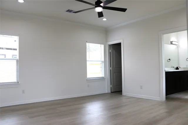 an empty room with wooden floor ceiling fan and windows