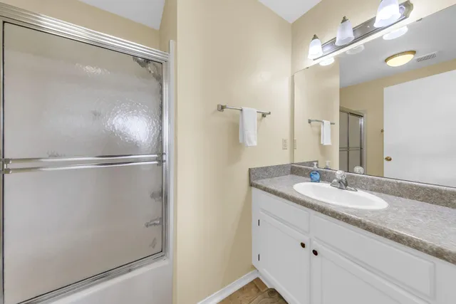 a bathroom with a granite countertop shower sink vanity and mirror