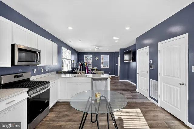 a kitchen with a dining table wooden floor and stainless steel appliances