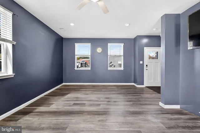 a view of an empty room with window and wooden floor