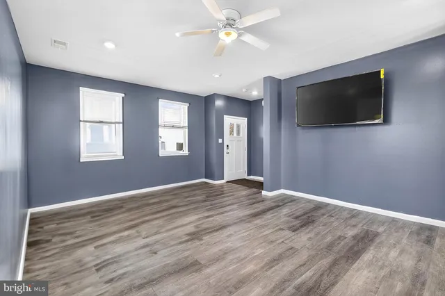 a view of an empty room with a window and a kitchen