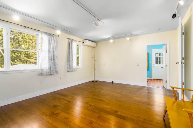 a view of an empty room with window and wooden floor