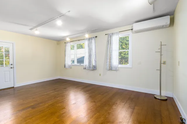 an empty room with wooden floor and windows
