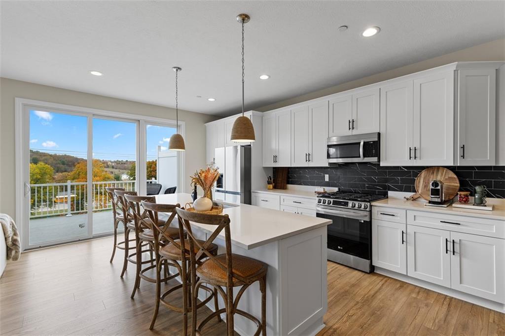 403 Walnut Court Pittsburgh, PA 15237 - Photo 12 of 42 a kitchen with stainless steel appliances granite countertop a stove a sink a microwave a dining table and chairs with wooden floor