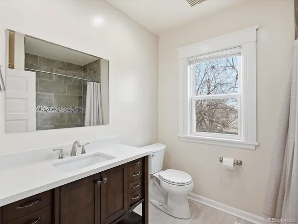a bathroom with a granite countertop sink toilet and a mirror