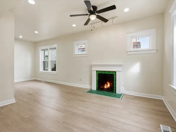 a view of an empty room with wooden floor fireplace and a window