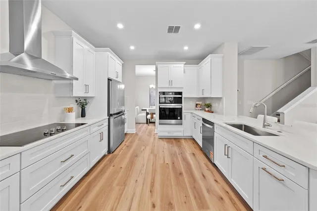 a large kitchen with stainless steel appliances and white cabinets