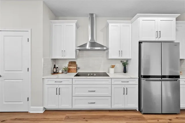 a kitchen with white cabinets and refrigerator