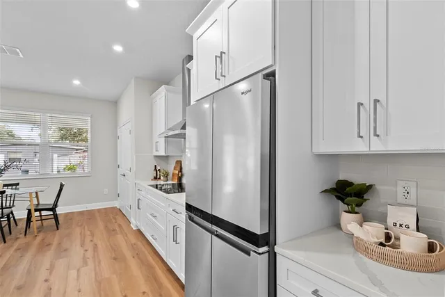 a kitchen with stainless steel appliances a refrigerator a sink a stove and white cabinets