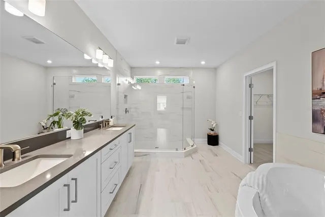 a spacious bathroom with a double vanity sink and mirror with shower