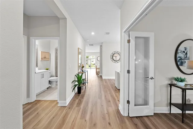a view of a hallway with wooden floor and a bathroom