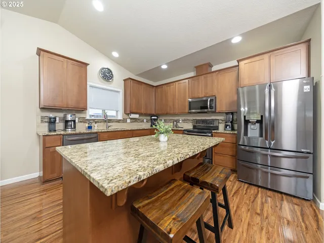 a kitchen with stainless steel appliances granite countertop a refrigerator a stove and a sink