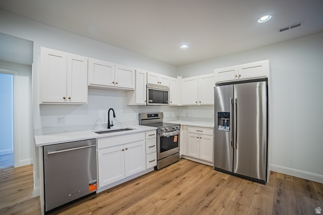 45 North Scarlet Maple Road, Unit 4317 Vineyard, UT 84059 - Photo 30 of 35 Modern kitchen featuring white shaker cabinetry, stainless steel appliances, light-toned countertops, wood-finish flooring, and recessed lighting