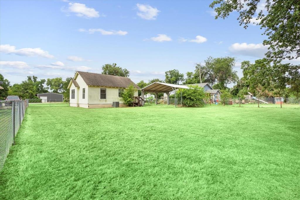 608 9th Street Hico, TX 76457 - Photo 16 of 23 Expansive grassy yard with chain-link fencing, a detached carport, and a structure with an exterior deck