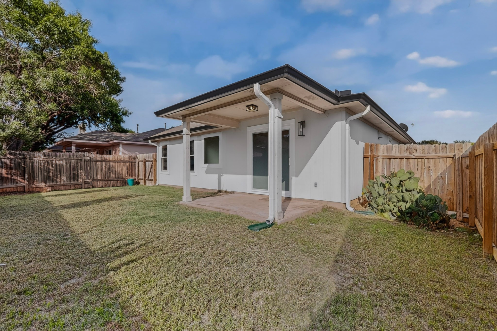 3906 Reeders Drive Austin, TX 78725 - Photo 33 of 36 Rear exterior featuring a covered patio with recessed lighting, an expansive lawn, and a perimeter wooden fence