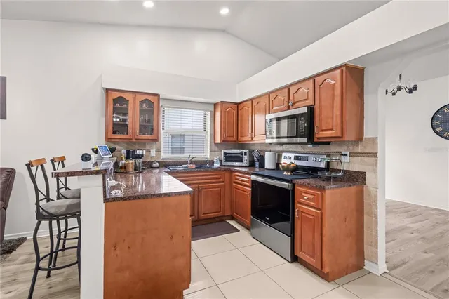 a kitchen with stainless steel appliances granite countertop a stove top oven a sink dishwasher and a refrigerator
