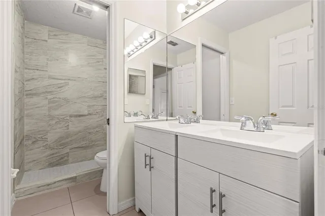 a bathroom with a double vanity sink a toilet and shower