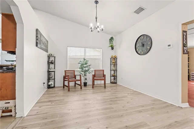 a view of dining room and livingroom with furniture wooden floor clock and a chandelier