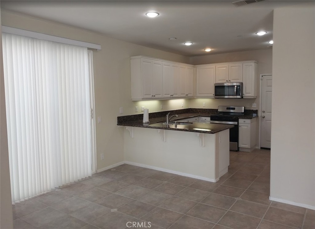 9772 Edenbrook Drive Riverside, CA 92503 - Photo 4 of 11 a kitchen with a refrigerator and a stove top oven