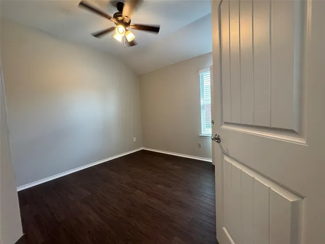 an empty room with wooden floor closet and windows