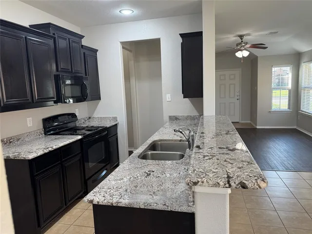 a kitchen with granite countertop a sink a stove and cabinets