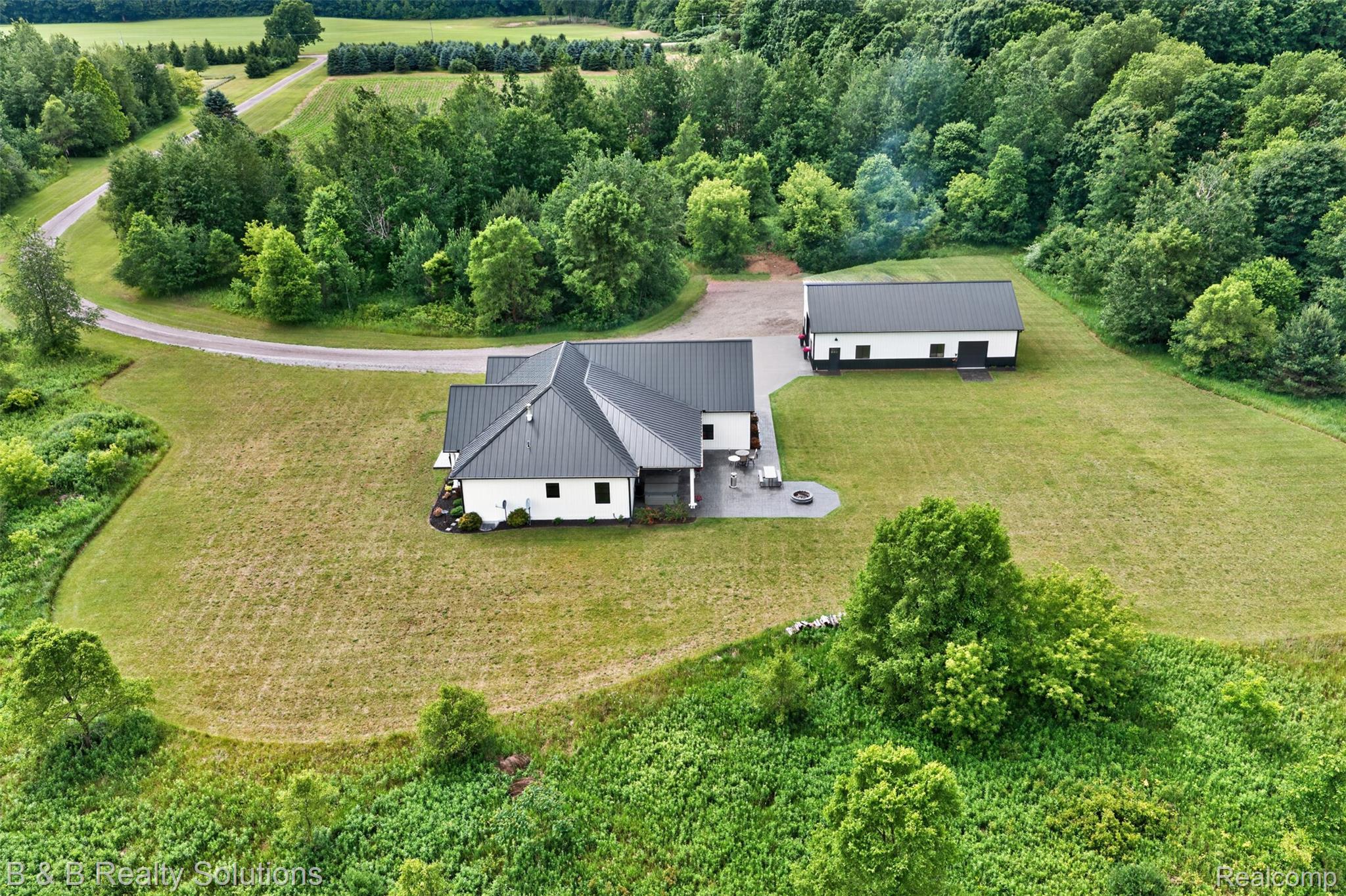 6204 Fish Lake Road North Branch, MI 48461 - Photo 65 of 79 Modern white-sided residence with a dark metal roof, set amidst an expansive green landscape