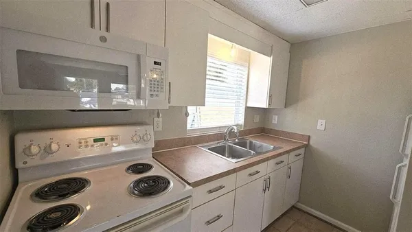 a kitchen with sink a stove and white cabinets