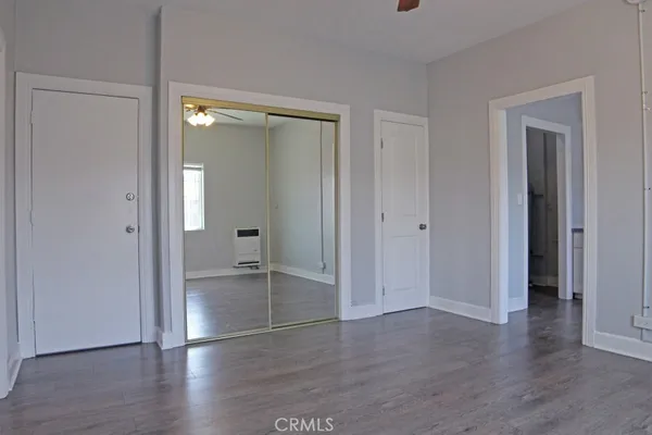 a view of an empty room with wooden floor and closet