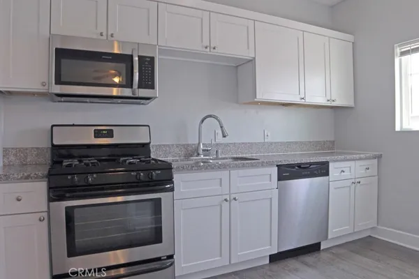 a kitchen with granite countertop white cabinets and white appliances