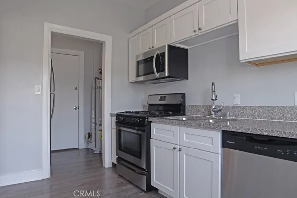 a view of a refrigerator in kitchen and white wooden cabinets