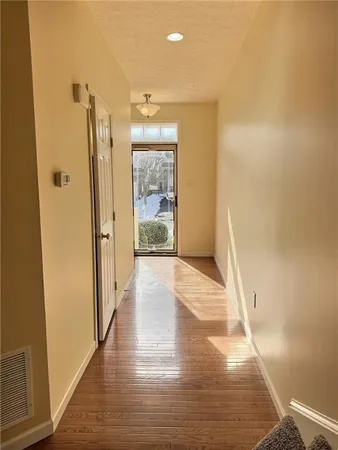a view of a hallway with wooden floor and a bathroom