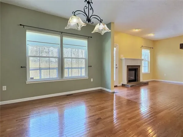 a view of an empty room with window and wooden floor