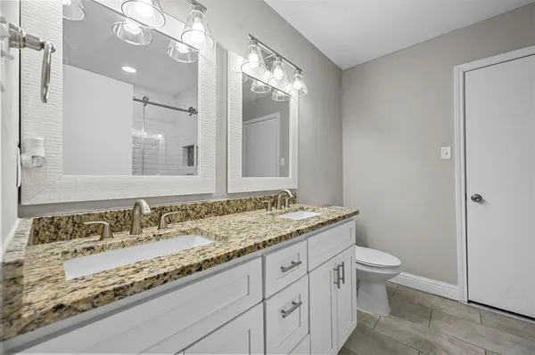 a bathroom with a granite countertop sink a toilet and a mirror