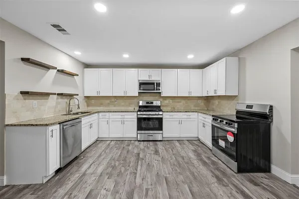a kitchen with granite countertop a stove top oven sink and cabinets