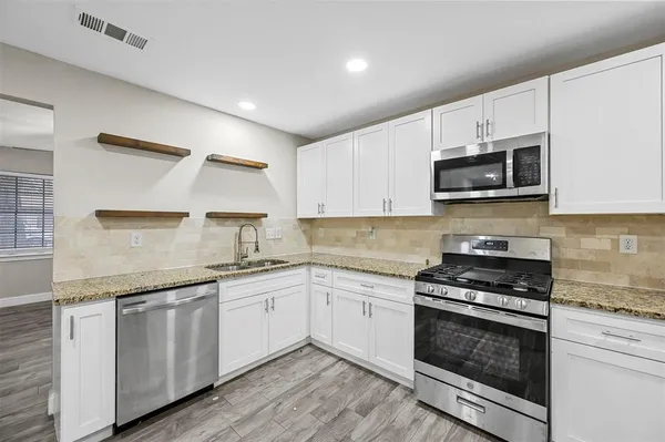 a kitchen with granite countertop a stove top oven sink and cabinets