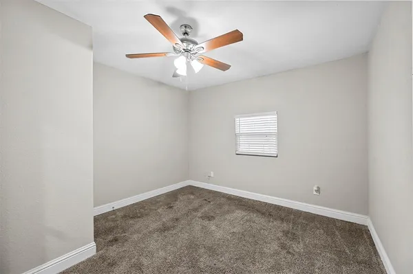 an empty room with a window and a fan