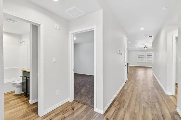 a view of a hallway with wooden floor and a living room