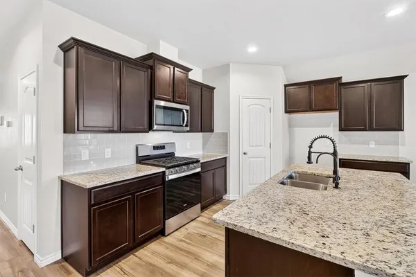 a kitchen with stainless steel appliances granite countertop a stove microwave and sink