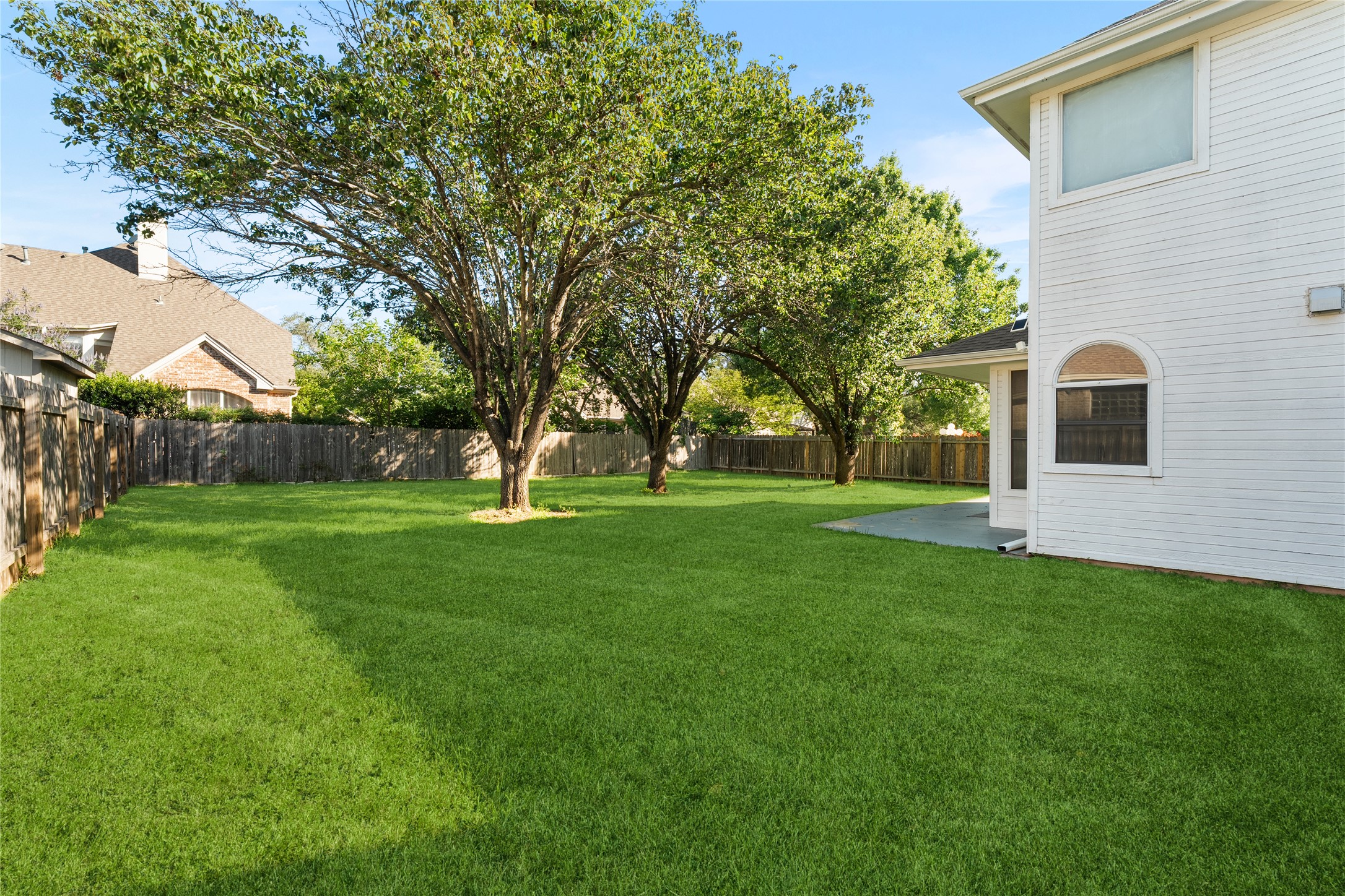 206 River Down Road Georgetown, TX 78628 - Photo 36 of 39 Spacious green lawn with mature trees, fenced perimeter, and a concrete patio
