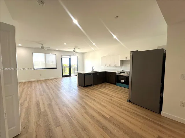 a kitchen with stainless steel appliances a refrigerator and a wooden floor