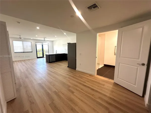 a view of an empty room with wooden floor and a window