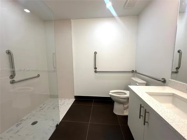 a bathroom with a granite countertop sink a toilet and a shower
