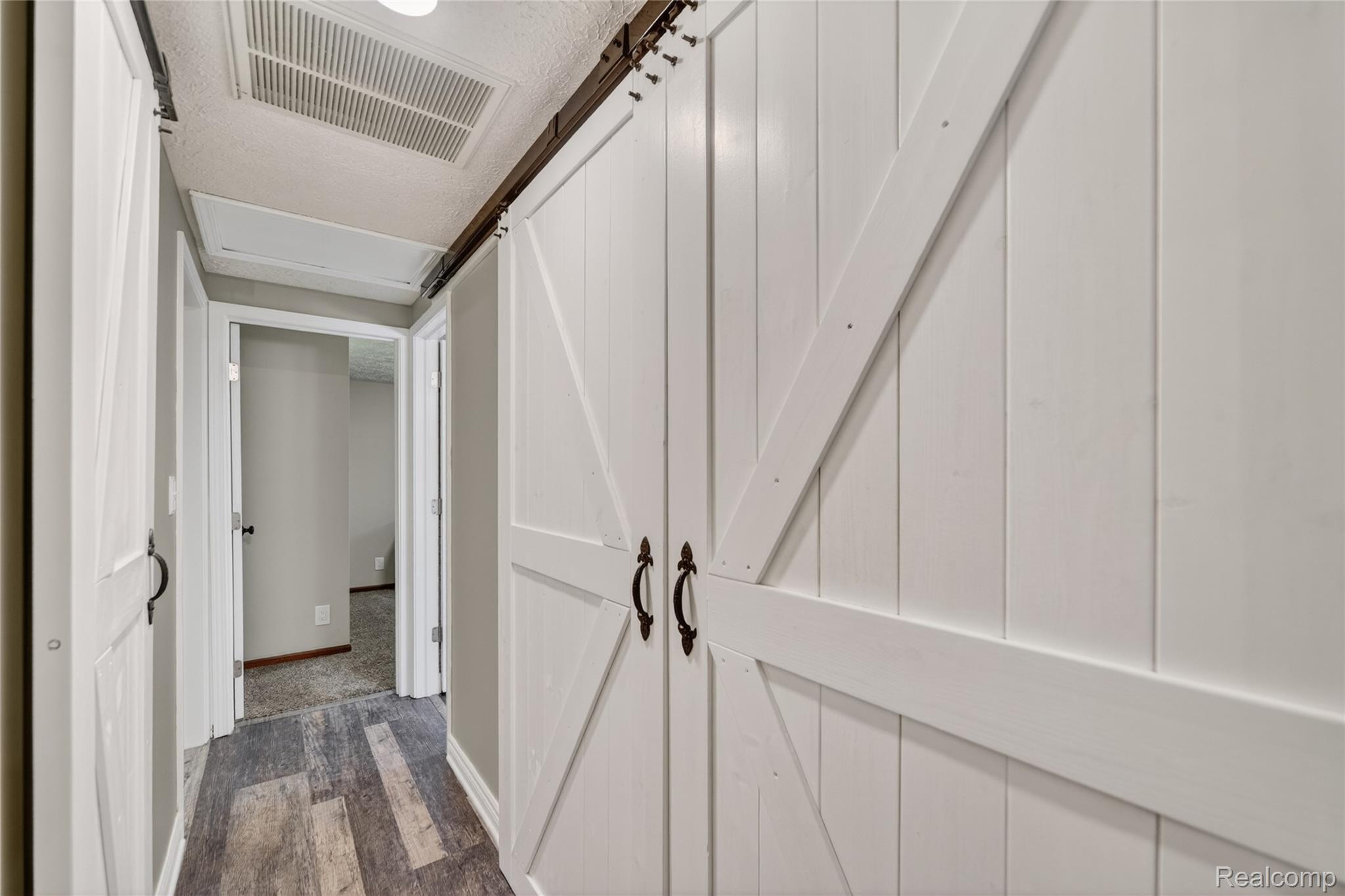 13635 Unadilla Road Gregory, MI 48137 - Photo 29 of 68 Hallway featuring wood-finish flooring, light gray wall paint, and white barn-style sliding doors with black hardware
