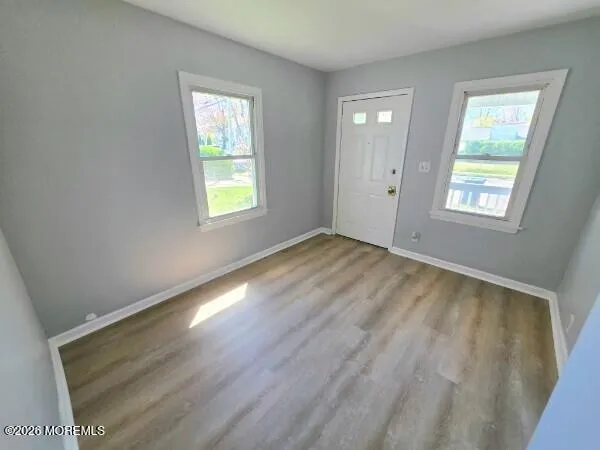 a view of an empty room with wooden floor and a window