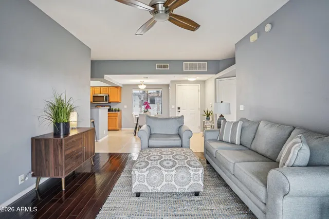 a living room with furniture large window and wooden floor