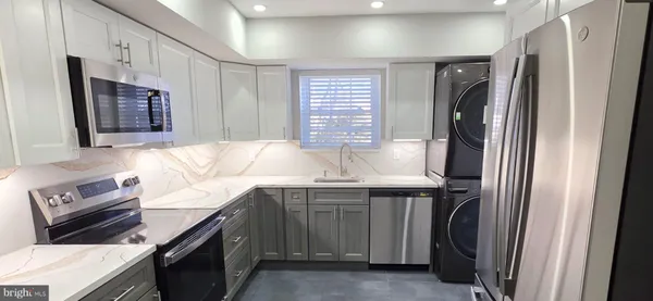 a kitchen with stainless steel appliances granite countertop a refrigerator a sink and a stove