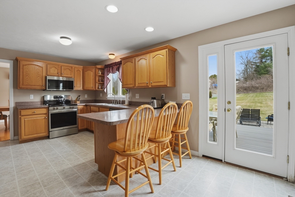23 Bridle Path Auburn, MA 01501 - Photo 14 of 40 a kitchen with granite countertop a stove a sink a dining table and chairs