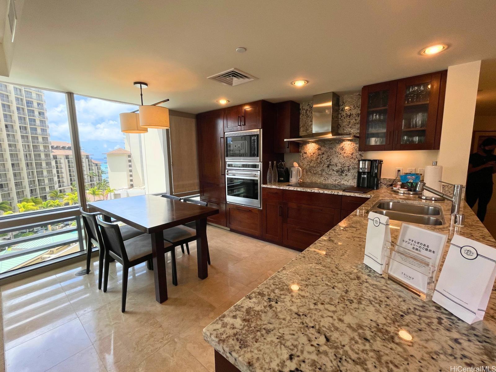 223 Saratoga Road, Unit 1102 Honolulu, HI 96815 - Photo 6 of 23 a kitchen with stainless steel appliances kitchen island granite countertop a table chairs sink and cabinets