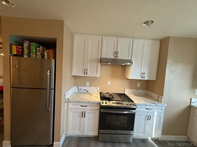a kitchen with stainless steel appliances granite countertop a refrigerator stove and white cabinets